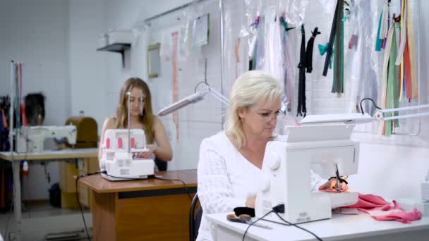 Женщины-коллеги используют швейные машины во время работы в портной мастерской — стоковое видео