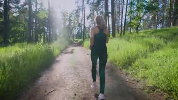 Mulher bonita correndo na trilha na floresta — Vídeo de Stock