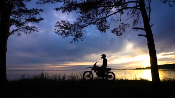 Figura del hombre en moto posando sobre el fondo de la puesta del sol — Vídeo de stock