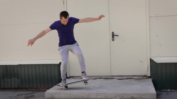 Imagen de un joven entusiasta de los deportes extremos que pasa su tiempo libre patinando al aire libre. Chico saltando sobre la barrera en el monopatín haciendo kickflip. Deportista usando tabla para hacer trucos en la calle . — Vídeo de stock