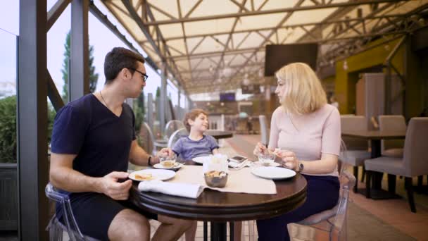 La famille profite du repas tous ensemble au restaurant, riant et bavardant les uns avec les autres — Video