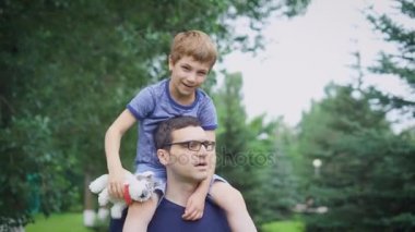 Veren oğlu yolculuk geri parkta Peder. Oğlum bırakacak onun omuzlarında ve bakarken mutlu baba portresi. Baba ve açık oynamak oyuncak sevimli çocuk.