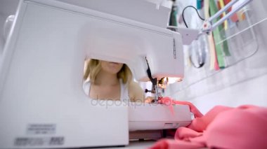 atış bir parça bir fabrikada bir elektrikli dikiş makinesi üzerinde pembe elbise diker terzi elin kapatın