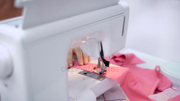 Primer plano del proceso de coser varias piezas de tela en una máquina de escribir eléctrica, las manos femeninas empujan la tela debajo de la aguja y el hilo — Vídeo de stock