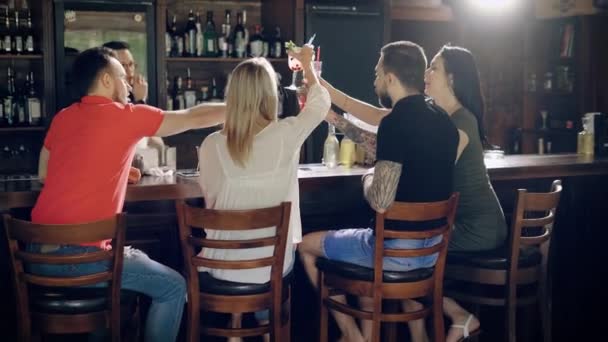 Amigos en el bar. Los jóvenes celebran, dicen brindis, beben cócteles . — Vídeo de stock