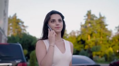 Yaz sezonunda onun arkadaşıyla telefonda konuşurken beyaz elbiseli bir gülümseyen güzel kadın portresi