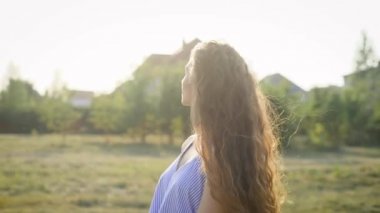 Çekici bir kadın parlak bir makyaj ile bir ülke sitesinde yürür, bir sarafan kadın saçlarını dokunur ve güvenle ileri bir ülke sitede gidiyor