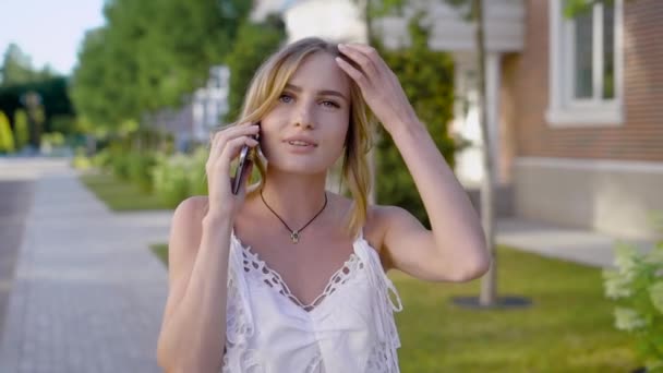 Joven rubia hablando por teléfono móvil con novia, mujer con maquillaje natural caminando por la calle — Vídeos de Stock