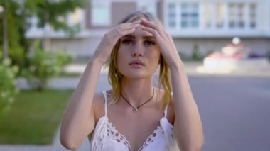 Bir yaz gününde, tasarımcı elbise giymiş bir kız sokakta yürürken yüzünde makyaj ile genç kadın