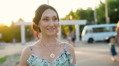 Genç mutlu esmer gülümseyen güneşli bir günde, road yakınındaki bir sokakta duran kamera hareket ediyor