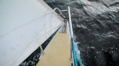 küçük yelkenli ile beyaz yelken burun koyu dalgalar sürme gündüz deniz, en baştan görüntülemek