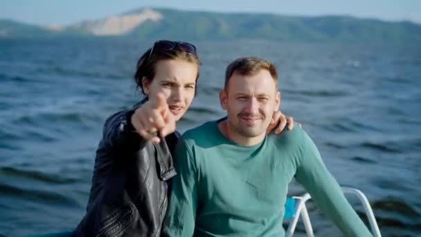 Young vrij omarmen paar is op een bord van het schip in een zee in zonnige zomerdag, glimlachen en op zoek naar een camera — Stockvideo