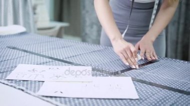 Genç kadın tasarımcı ayakta dikmek Studio tebeşir ve kural bezle satırları yapma masada kapatın. Atelier kesmek bir desen moda elbise için çalışan kadın terzi.