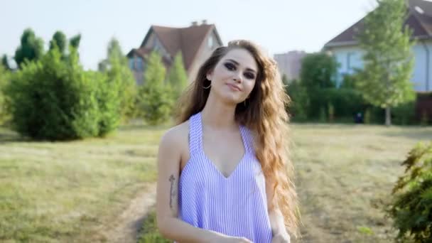 Mulher jovem e bonita está feliz andando pelo campo, sorrindo, rindo e aproveitando os últimos dias do verão — Vídeo de Stock