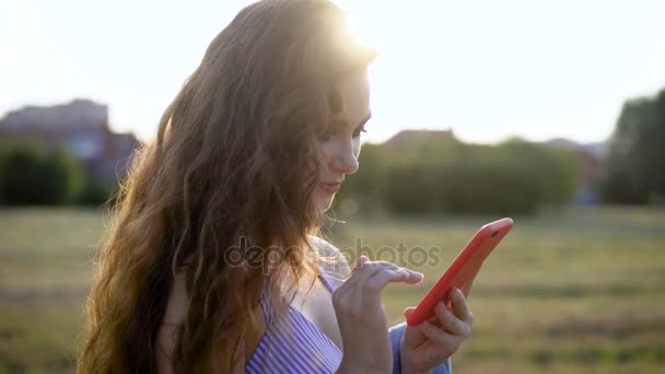 Utestående kvinna står ensam i fältet och använda smartphone, skrattar och chatta med vänner — Stockvideo