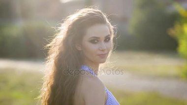 Uzun kahverengi saçlı güzel genç çekici kadın seksi bir görünüm vermek için güneş'ten geri döner