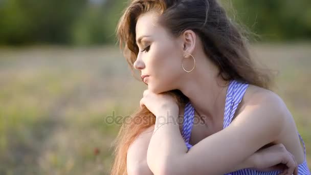 Одна красивая женщина сидит посреди поля очень расстроенная и совершенно одинокая, думая о жизни. — стоковое видео