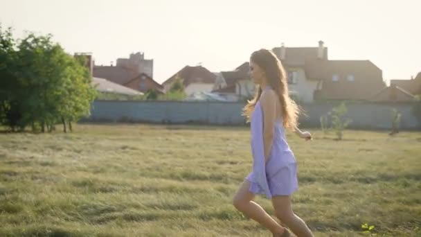 Sehr glückliche junge schöne Frau, die allein über das Feld läuft, Kleid trägt und ihr Leben genießt — Stockvideo