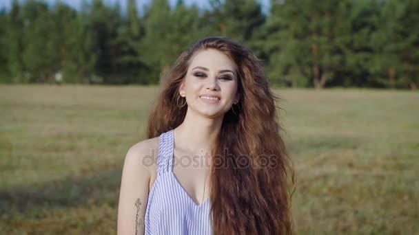 Молодая и красивая женщина счастливо ходит по полю, улыбаясь, смеясь и наслаждаясь последними днями лета — стоковое видео