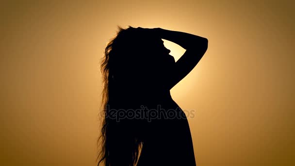 Jovem e inacreditavelmente bela mulher sozinha, desfrutando pacificamente de um dos últimos pôr-do-sol de verão penteando o cabelo para trás — Vídeo de Stock