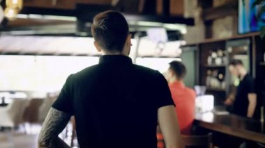 Gencin tattoed elleri arkadan görünüm café arkadaşlarına yürüyüş siyah t-shirt giymiş. İki kadın ve bir adam geldi eşini onu kucaklayan sıcak karşılama masada oturan