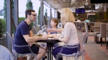 Açık teras masada oturan birlikte vakit oğluyla mutlu çift. Karısı ve kocası milkshake içme çocuk konuşuyor. Genç anne ve çocuk bir restoranda öğle yemeği zevk.