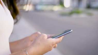 Kadın el smartphone üzerinde sokak arka plan bulanık yaz aylarında kullanarak kırpma yakın çekim vurdu.