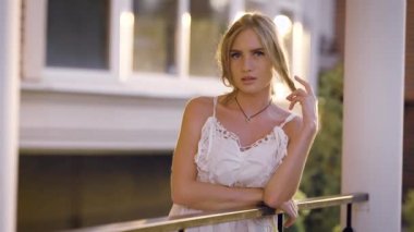 Beyaz saç ile oynayan ve sokak kameraya bakarak çit yaslanmış genç şehvetli modeli portresi.