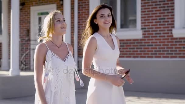 Young women walking down street in summer sunlight and chatting. — Stock Video