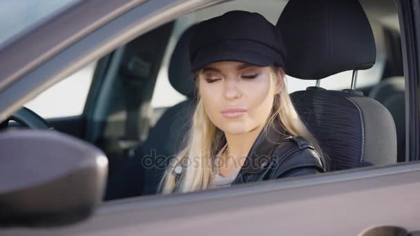 Uma mulher jovem e atraente senta-se ao volante de um carro, talvez uma senhora está presa dentro de seu veículo — Vídeo de Stock