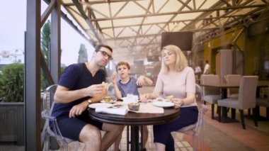 Çocuk ailesiyle birlikte oturan ve kafeterya terasta yemek