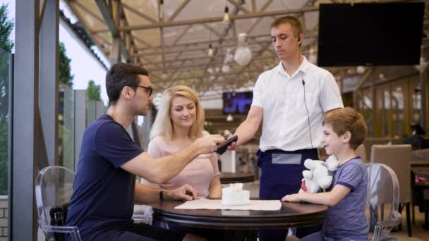 Man met credit card betalen voor ober tijdens een diner met familie in restaurant — Stockvideo