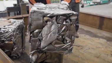Yerdeki üretim daha fazla kullanmak için preslenmiş metal bloklar özel üniformalı birkaç adam atmak