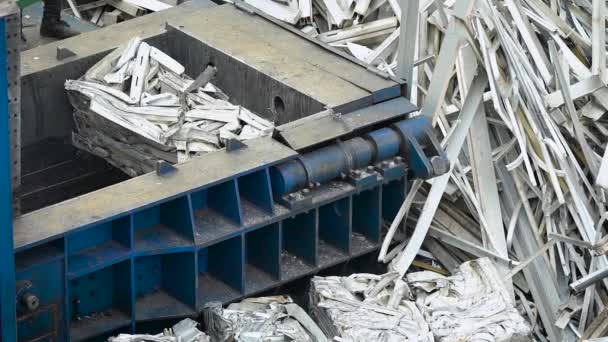 Металлический мусор и мусор обрабатываются на заводе, машина поднимает прессованные металлические пластины на другую кучу блоков — стоковое видео
