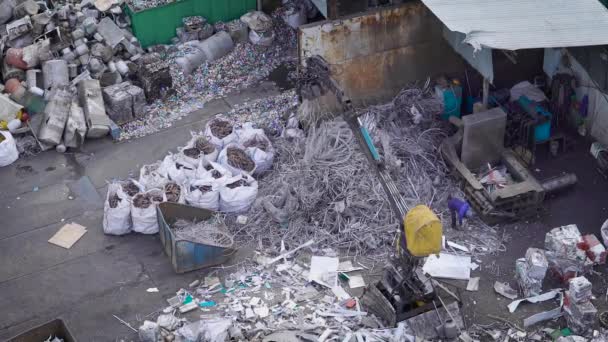 The process of processing materials, the machine where a person sits, raises garbage and shifts it into a metal basket — Stock Video