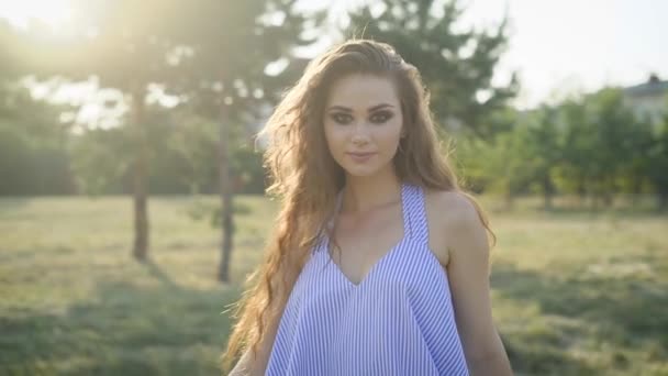 Retrato de mulher bonita em casual posando no campo e olhando para a câmera à luz do sol . — Vídeo de Stock