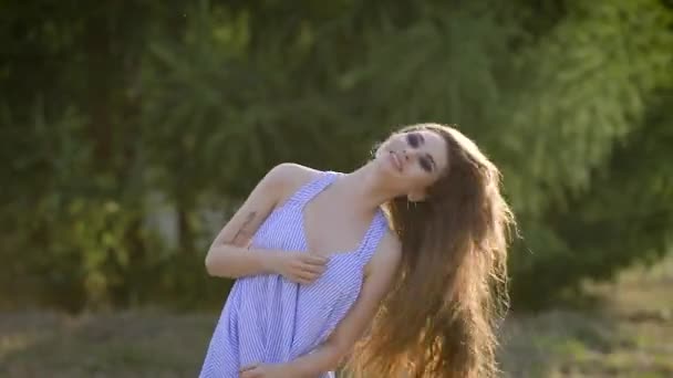 Young stylish girl with makeup shaking head and waving long hair on natural background. — Stock Video