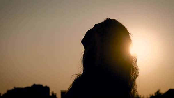 Anonieme vrouw met lang haar poseren, sensueel en gooien terug haar hoofd tegen zonsondergang licht. — Stockvideo