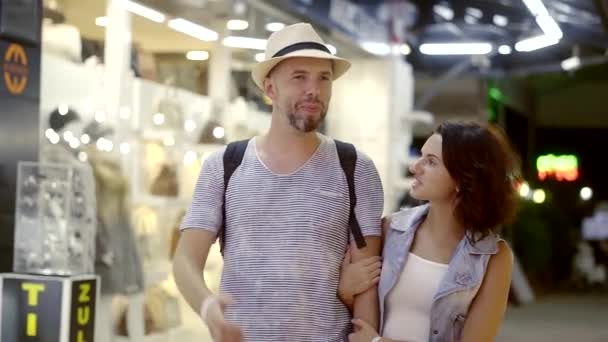 A happy man and woman are walking in the evening market. A couple on vacation went shopping, they choose souvenirs and things. Bazar — Stock Video