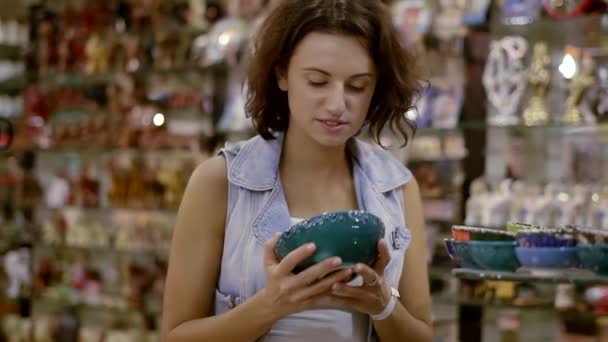 Una ragazza in un negozio di souvenir orientale. Una bella bruna sceglie un souvenir da un viaggio verso est . — Video Stock