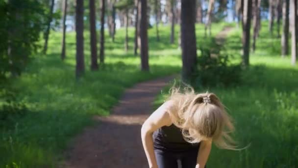 Mujer joven en deportista corriendo por el camino en el bosque de verano — Vídeos de Stock