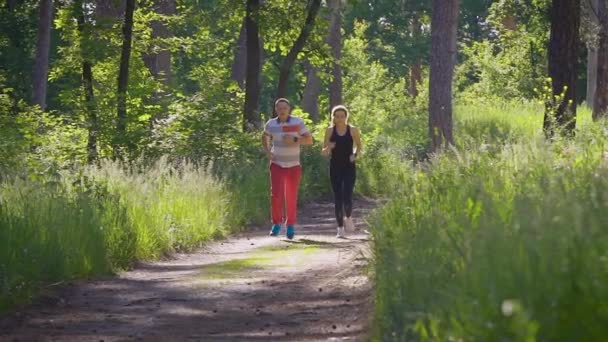 Scatto al rallentatore di una coppia sposata che corre nel parco, il marito e sua moglie stanno correndo attivamente per portare il corpo in una buona forma fisica — Video Stock