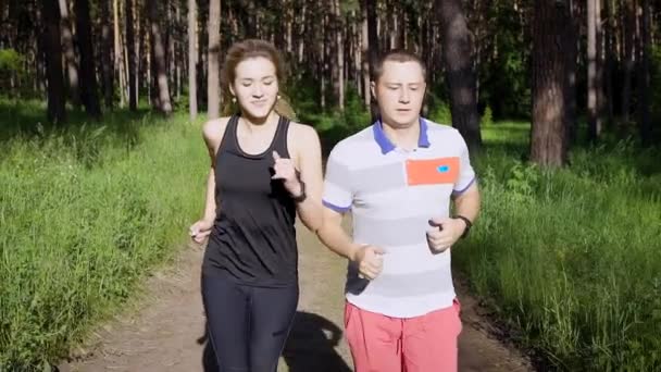 Junger Mann und Frau laufen gemeinsam durch sommergrüne Wälder — Stockvideo