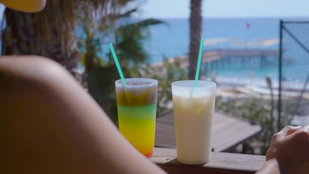 Mujer disfruta de la vista del mar en una terraza con dos cócteles — Vídeos de Stock