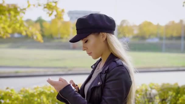 Jonge stijlvolle model met wandeling in stadspark met smartphone — Stockvideo
