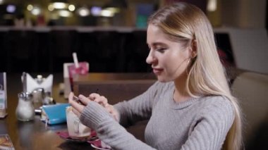 Kafede kahve içer ve telefon masada izlerken kadın