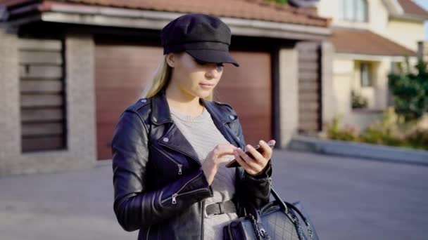 Trendy aantrekkelijke model poseren en het gebruik van smartphone bij herfst street — Stockvideo