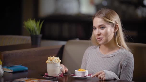 Vrolijke vrouw met heerlijke snack in moderne café poseren gelukkig — Stockvideo