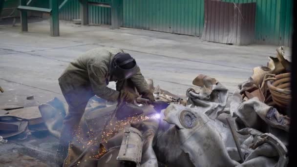 Un travailleur utilise une torche à oxygène pour couper un gros objet métallique en morceaux dans une usine de recyclage de métaux — Video