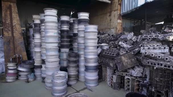 Uma pilha de jantes e blocos de motor deitados juntos em um armazém . — Vídeo de Stock